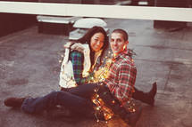Happy couple wrapped in Christmas lights