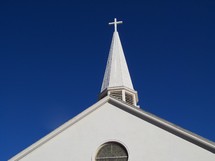 White Cross on a church steeple against a clear blue sky