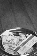 cash and envelopes in an offering plate