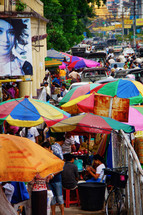 Colored umbrellas on a busy sidewalk during market day