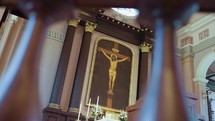 Slow-motion pan looking at Jesus on a cross through church columns during mass.
