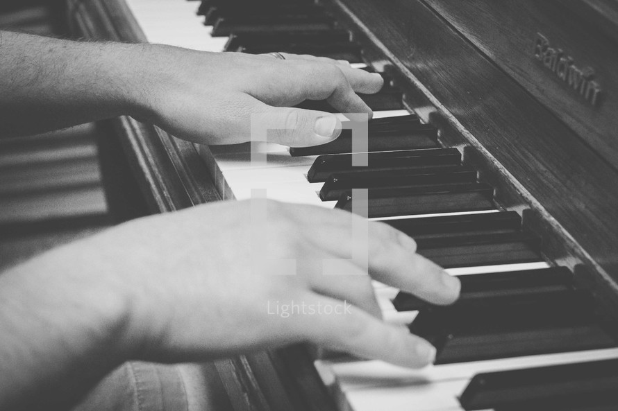 Hands playing a piano.