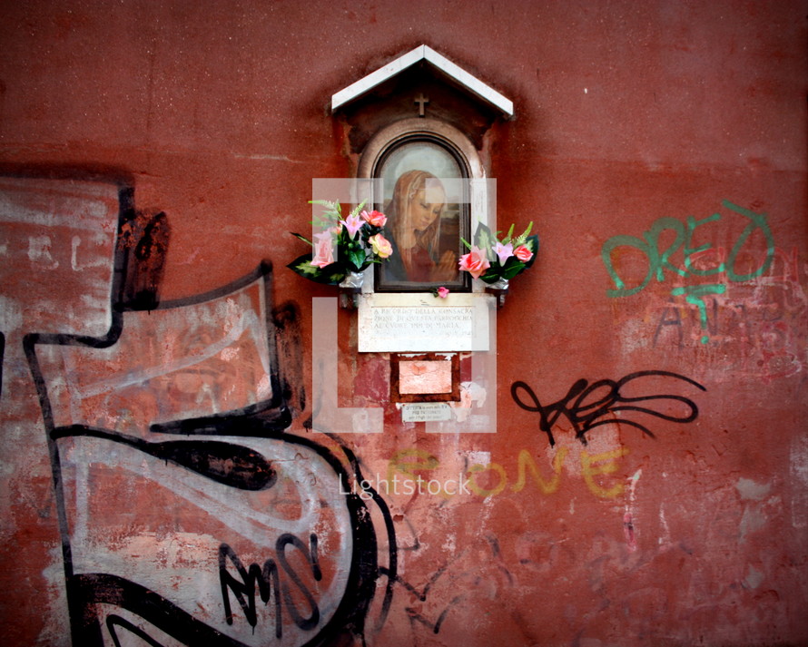 A street shrine on a wall with graffiti