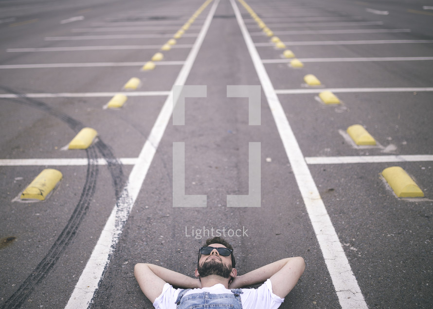 man lying down in a parking lot 