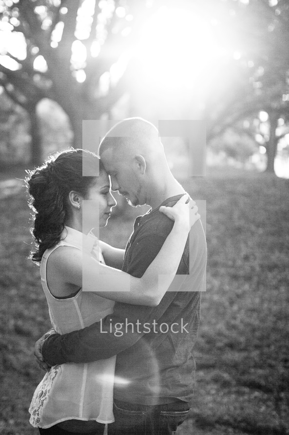 Couple embracing in the sun at a park.
