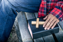 a man sitting next to a Bible and wooden cross 