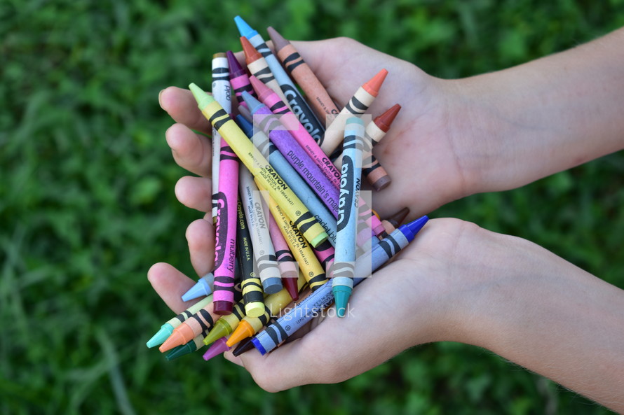 cupped hands holding crayons 