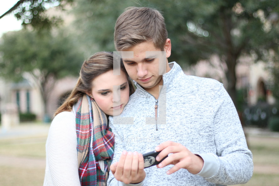 a young couple looking at a cellphone screen 