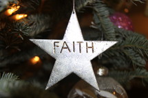 Star ornament with the word Faith hanging on a Christmas tree 