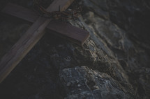 wooden cross and crown of thorns on a rock 