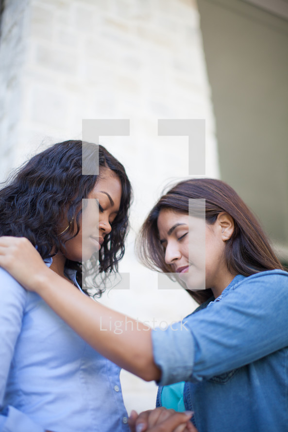 Two young women praying together.