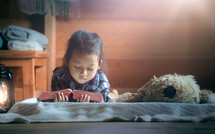 little girl reading the Bible with light in morning at home