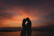 silhouettes of bride and groom on a beach at sunset 