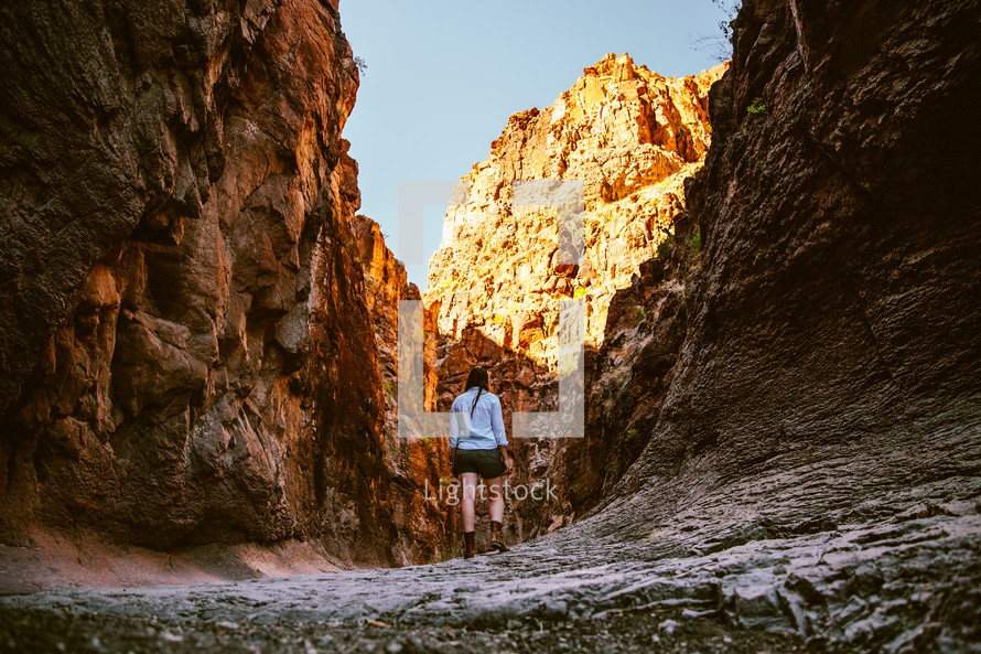 A woman hiking among steep cliffs.