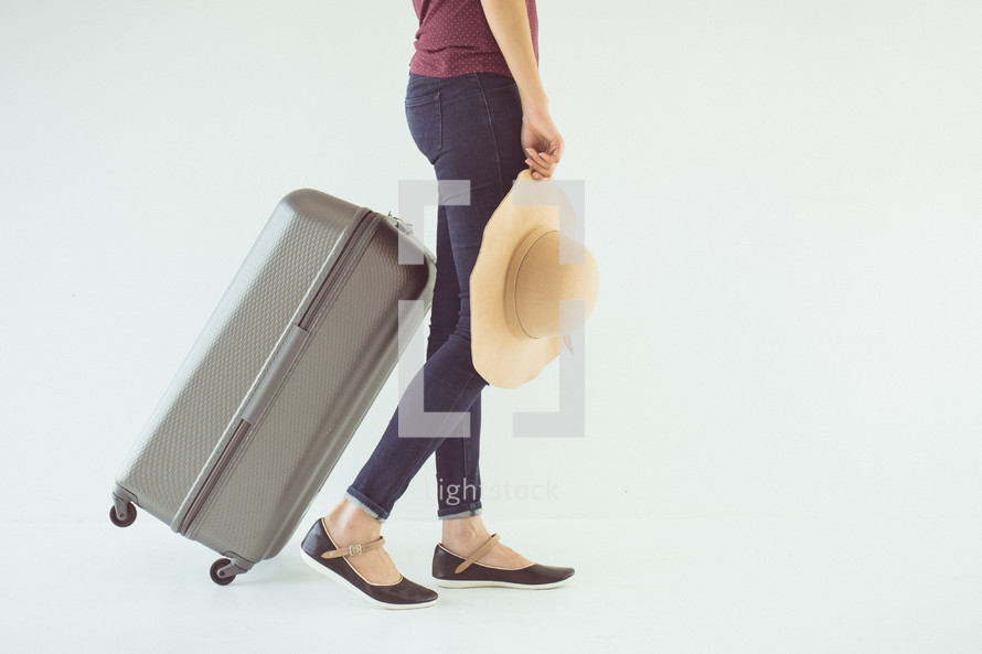 a woman with a sunhat carrying a suitcase 
