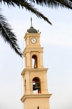 A church steeple with a cross, clock, and bell tower.