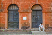 man sitting on a step in front of a brick building
