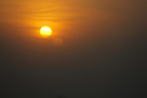 Sun in a hazy sky just about to slip below the horizon