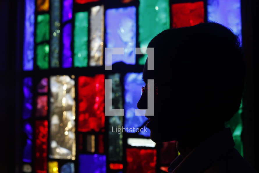 silhouette of a man's head and a stained glass window 