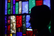 silhouette of a man's head and a stained glass window 