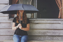 a girl sits alone with umbrella