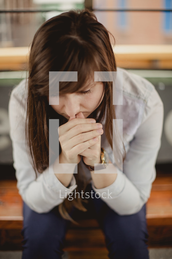 a young woman with head bowed in prayer 