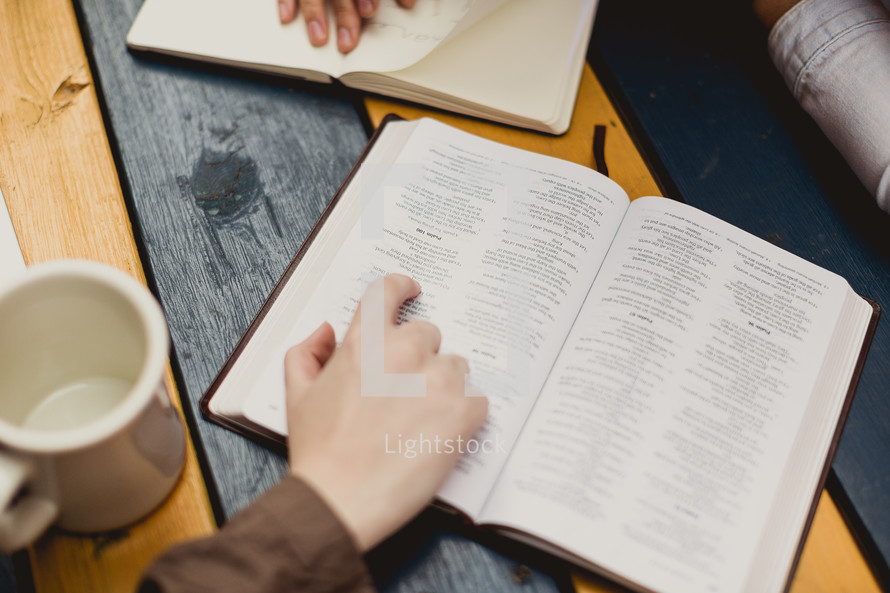 woman reading a Bible and writing in a journal 