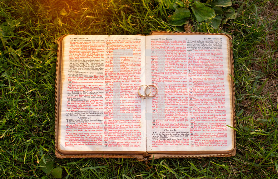wedding rings on pages of a Bible in the grass