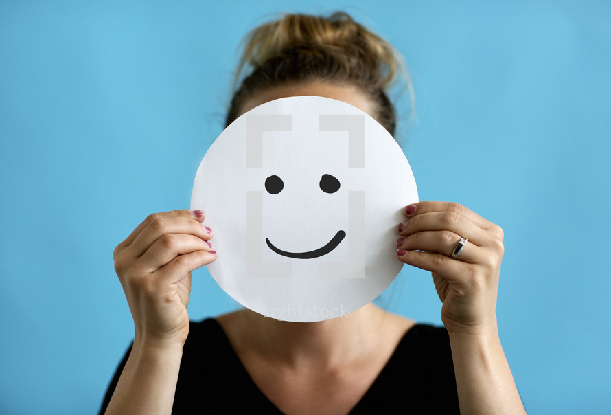 a woman holding up a smiley face 