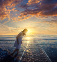 woman walking in the tide at sunrise 