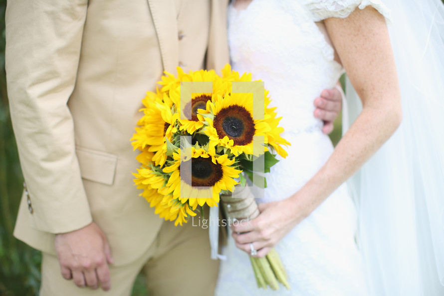 bride and groom and a bouquet of sunflowers 