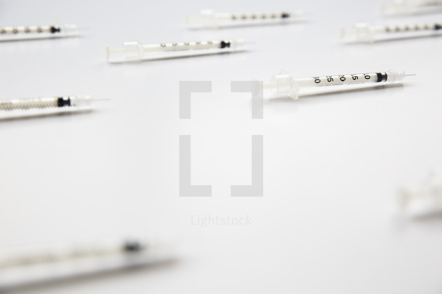 Hypodermic needles spread on a white surface.
