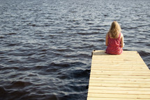 woman reading a Bible sitting at the end of a dock
