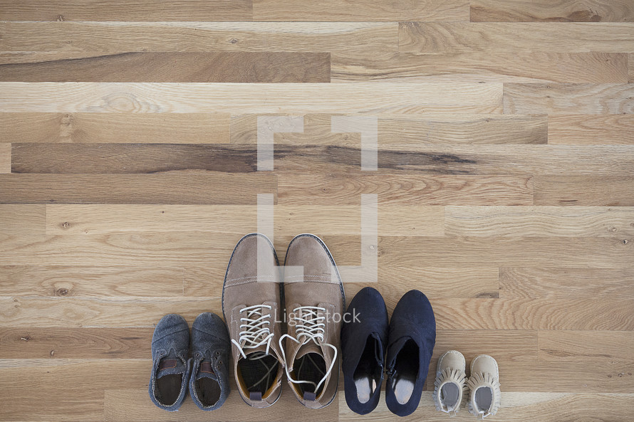pairs of difference sizes of shoes on a wood floor