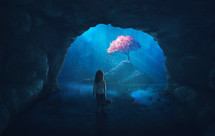 Little girl in cave looks at a beautiful cherry tree