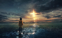 A little girl stands in the rain with a glowing cross in the sky