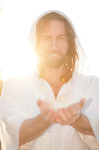 Smiling Jesus with outreached hands in the sunlight.