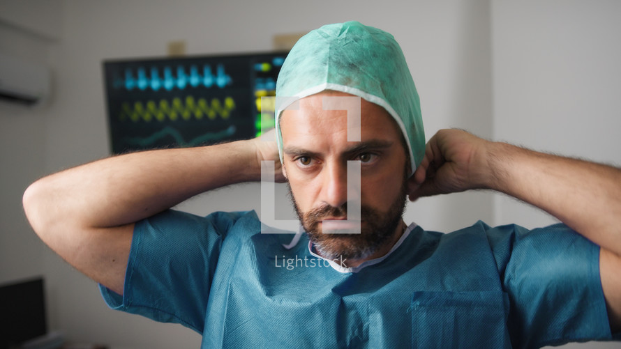 Surgeon wears green surgical cap