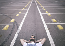 man lying down in a parking lot 