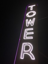 A tall neon sign with the word "Tower."