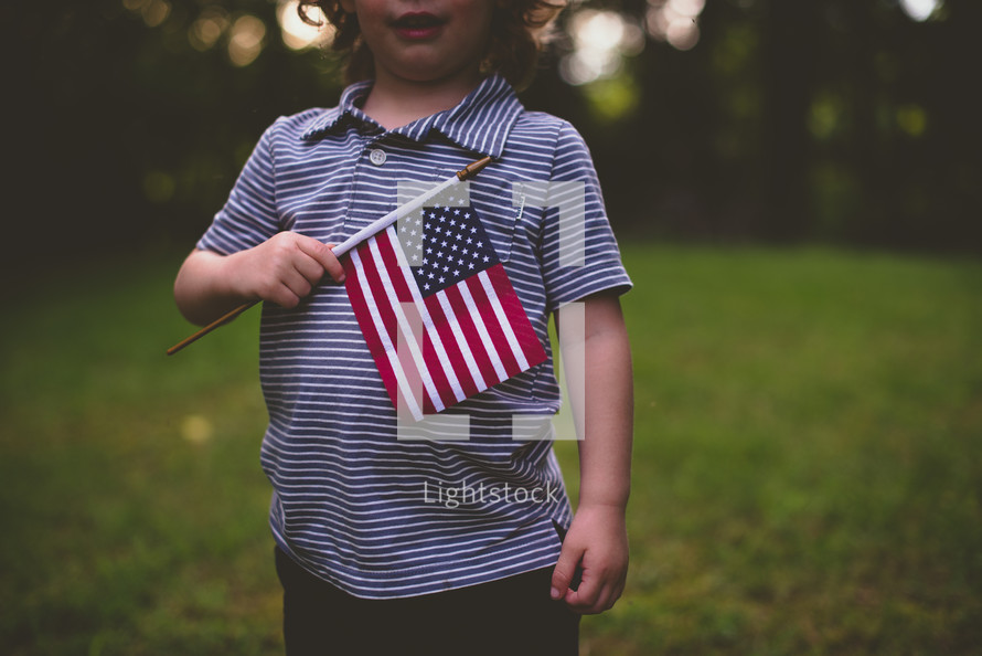 toddler holding an American flag over his heart 