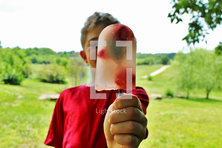 a boy holding a popsicle 