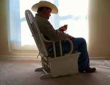 A single man stares at a toy thinking of a loved one or child as he sits in a rocking chair  alone. Loneliness and solitude are things that some people relish and others hate as it is hard being alone during difficult times such as fear of the unknown,  viruses, unexpected events or just every day life in a busy world. 