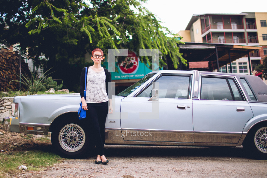 A woman standing in front of an old car. 