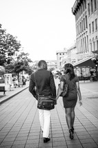 a couple walking on a sidewalk holding hands 