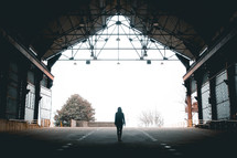a woman standing under a covered roof looking out at the fog 