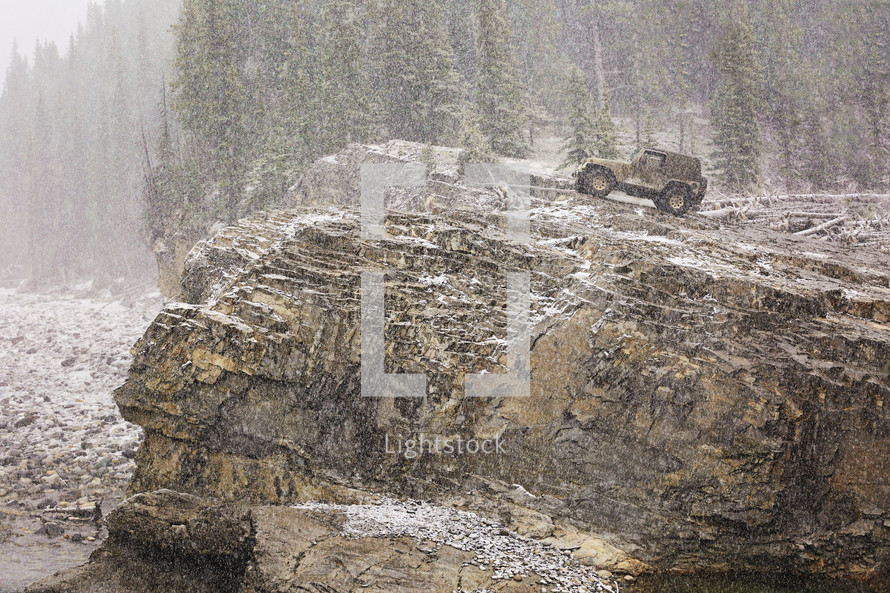 4 x 4 perched on a rocky cliff in a snowstorm