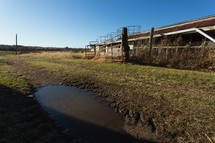 Water puddle in front of rusty, metal farm structure
