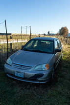 Old honda next to fence in rural area