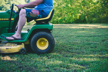 driving a lawnmower, cutting the grass